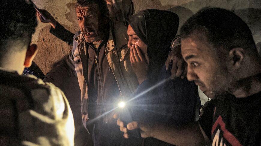 Palestinians gather around a wounded relative as rescuers search for people under the rubble of a Rafah home