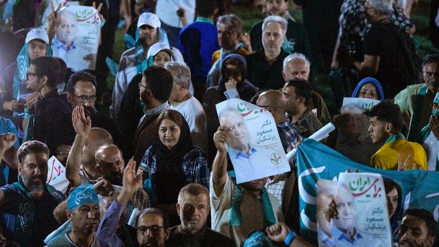 Supporters of reformist Iranian presidential candidate Massoud Pezeshkian raise his portrait during a rally in Tehran