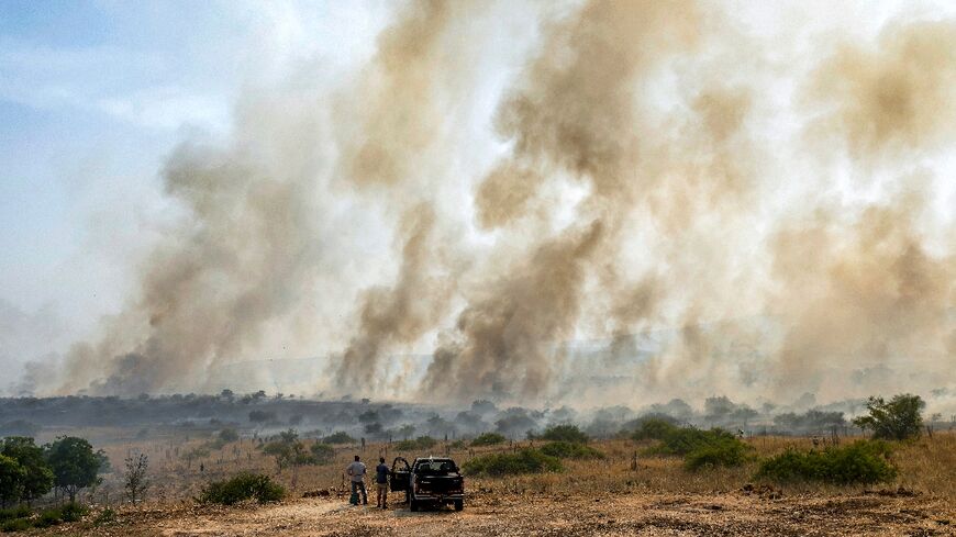 Onlookers watch smoke from burning fields after rockets fired from south Lebanon hit near Katzrin in the Israel-annexed Golan Heights