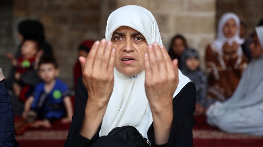 a Palestinian woman performs the Eid al-Adha morning prayer in the courtyard of Gaza City's historic Omari Mosque that was heavily damaged in Israeli bombardment 