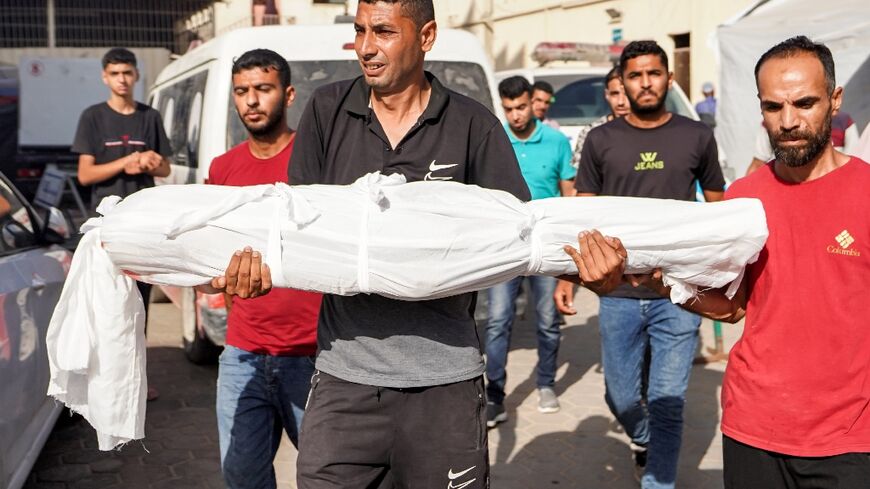 A man carries the body of Abdelrahman Yussef Abu Galambo, 11, who died during Israeli bombardment in Bureij refugee camp, central Gaza