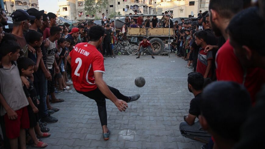 A crowd watches on as a footballer takes a penalty in Gaza's Jabalia refugee camp