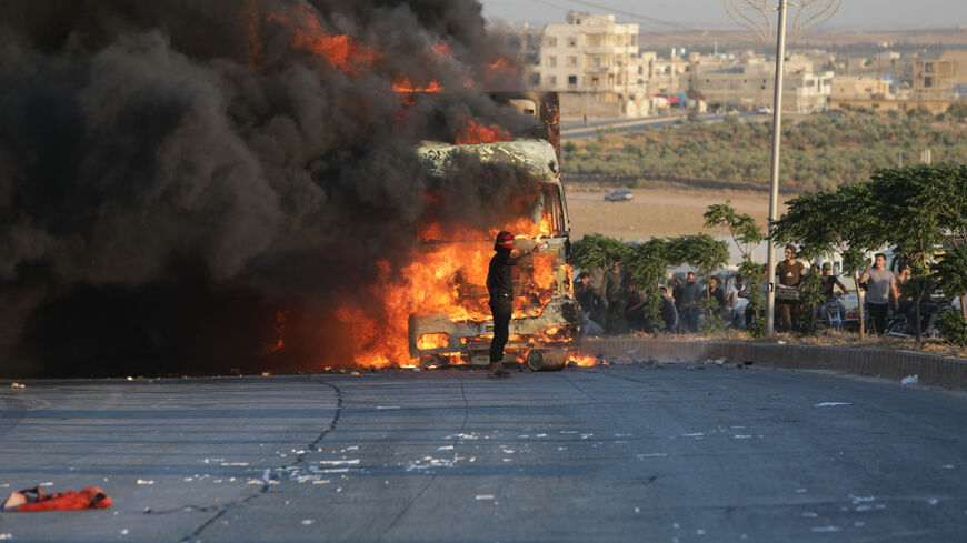 A protester stands in front a burning Turkish truck during protests against Turkey in al-Bab, in the northern Syrian opposition held region of Aleppo on July 1, 2024. A man was killed after and Turkish forces clashed in Syria's Ankara-controlled northwest , a war monitor said, in demonstrations sparked by violence against Syrians in Turkey a day earlier. (Photo by Bakr ALKASEM / AFP) (Photo by BAKR ALKASEM/AFP via Getty Images)