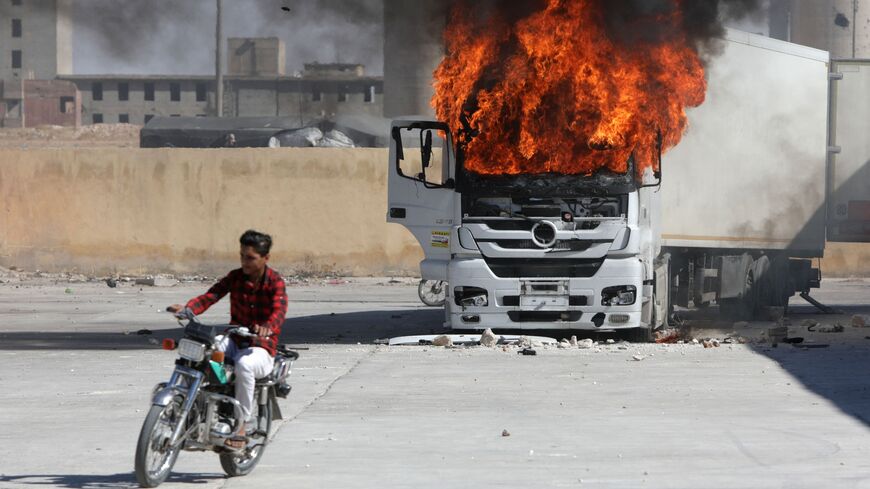 A man rides a motorcycle near a burning Turkish truck during protests against Turkey in al-Bab, in the northern Syrian opposition held region of Aleppo on July 1, 2024.