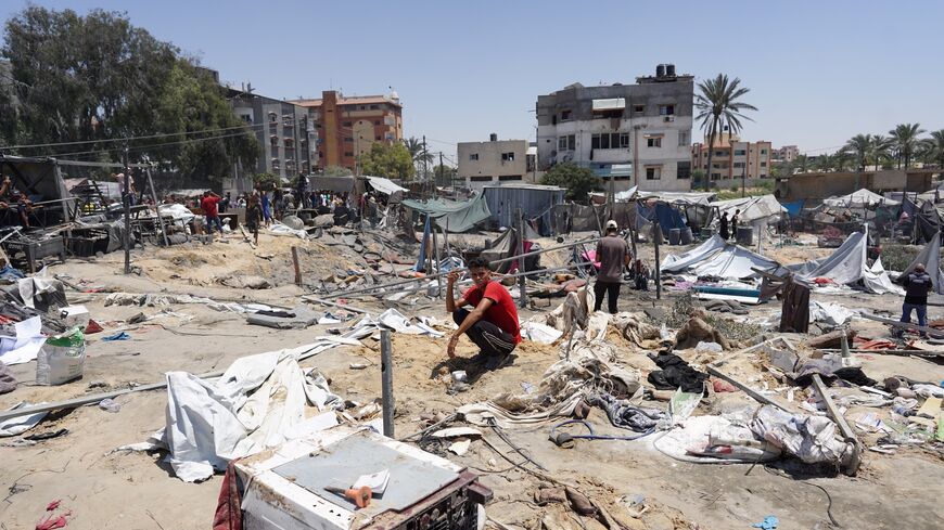 A Palestinian crouches as he surveys the debris of destroyed tents and make shift housing structures near a crater, following an Israeli military strike on the al-Mawasi camp for internally displaced people (IDP), near the city of Khan Yunis, southern Gaza Strip on July 13, 2024. 