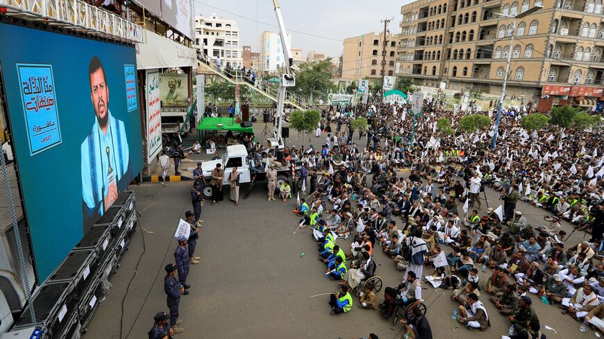 Members of Yemen's security forces stand guard as as Shiite Muslims listen to a speech by Houthi leader Abdul-Malik al-Huthi broadcast on a giant screen during a ceremony commemorating Ashura, July 16, 2024. 