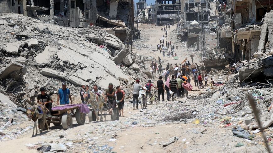 Palestinians walk past destroyed buildings in Gaza City's Shujaiya neighbourhood after the Israeli military withdrew from there after a two-week offensive 