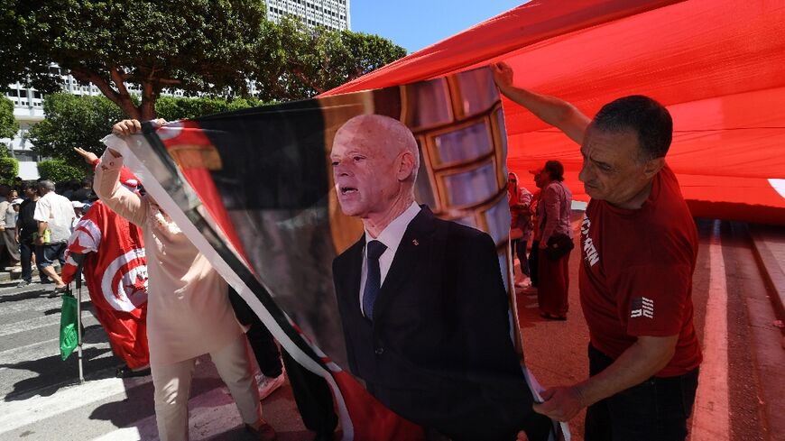 Supporters of Tunisian President Kais Saied hold his image during a rally along the Habib Bourguiba Avenue in Tunis, on July 25