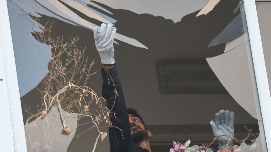 An Israeli policeman collects glass shrapnel from the window of a building that was damaged in an explosion in Tel Aviv