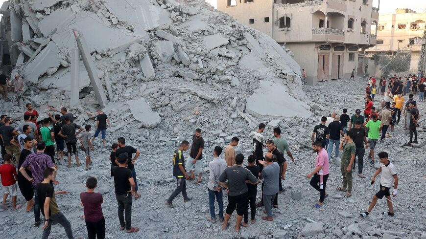 Palestinians check the remains of a building shortly after Israeli bombing levelled it in Nuseirat refugee camp, central Gaza