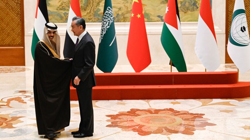 China's foreign minister, Wang Yi (R), shakes hands with Saudi Arabia's foreign minister, Prince Faisal bin Farhan Al-Saud, before a family photo for the attendees of a meeting of foreign ministers from Arab and Muslim-majority nations at the Diaoyutai State Guest House in Beijing on November 20, 2023. 