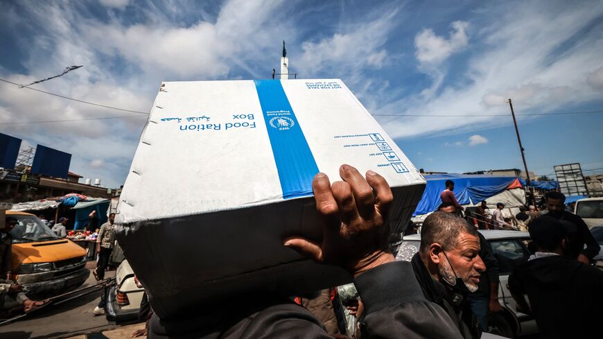 Displaced Palestinians carry a box of food rations provided by the World Food Program at a makeshift street market in Rafah in the southern Gaza Strip on March 14, 2024, amid ongoing battles between Israel and the militant group Hamas. 