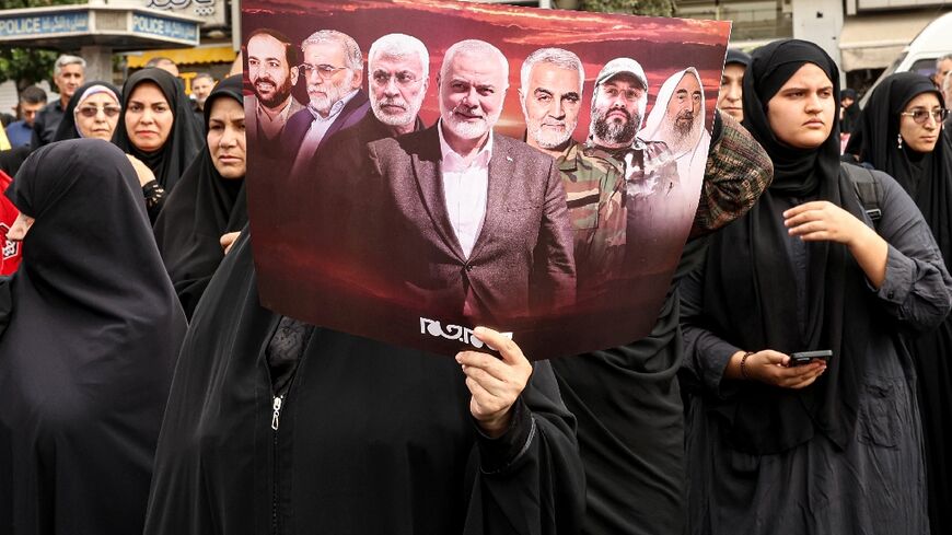 An Iranian woman holds a poster displaying slain militant leaders including Hamas's Ismail Haniyeh during his funeral procession in Tehran