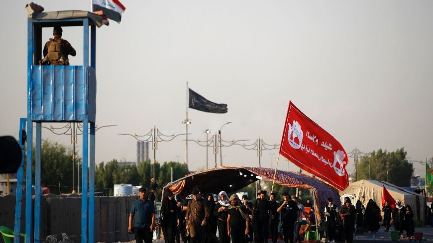 A member of the Iraqi security forces stands guard as Shiite Muslim pilgrims walk near Baghdad on their way to Karbala ahead of Arbaeen commemorations 