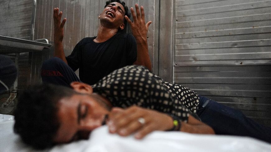 Palestinians mourn over the body of a relative killed in an Israeli strike, in southern Gaza's Khan Yunis