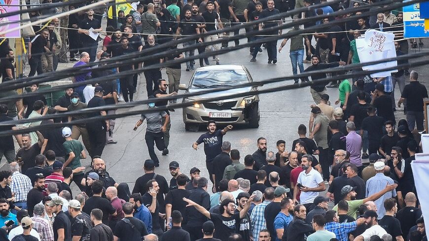 People run for cover after a blast sounded during a funeral in south Beirut for those killed in pager explosions the day before