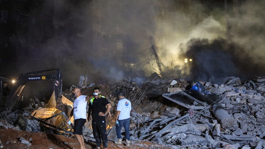 Rescuers inspect the rubble of a building destroyed in the Israel strike on Beirut's southern suburbs