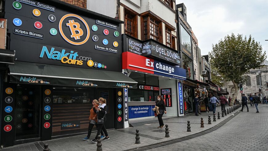 People pass by a cryptocurrency exchange branch near the Grand Bazaar in Istanbul on Oct. 20, 2021, a day after Bitcoin took another step closer to mainstream investing with the launch of a new security on Wall Street tied to futures of the cryptocurrency. 