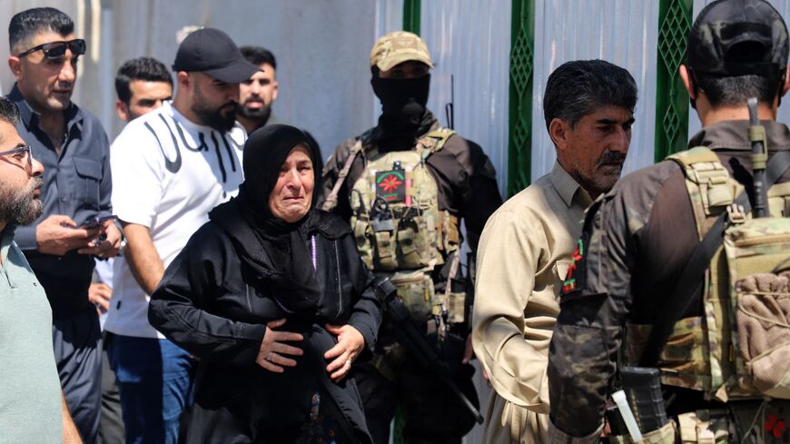 The mother (C) and father (2-R) of one of two women journalists killed in a drone strike walk past Kurdish Asayish security forces.