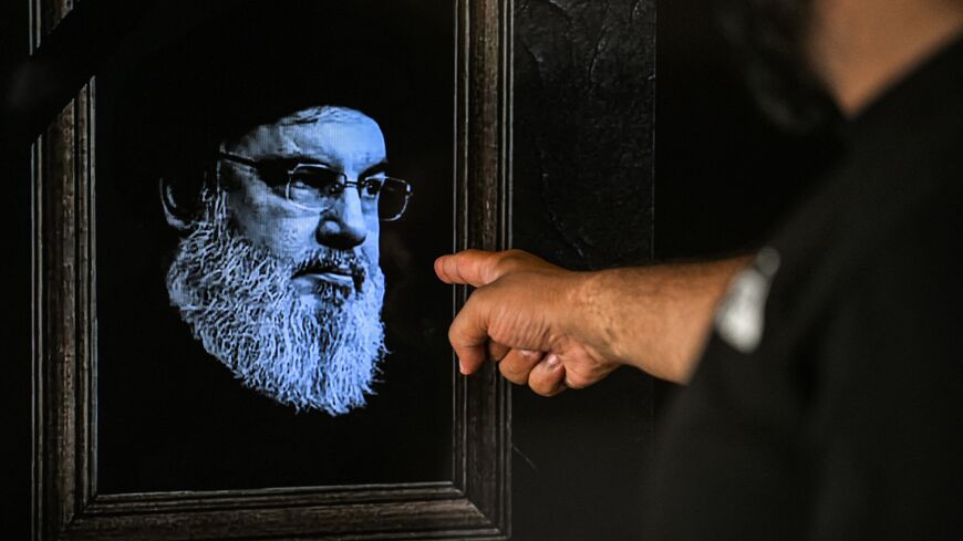 A man points to a television set displaying an image of the late leader of Hezbollah, Hassan Nasrallah.