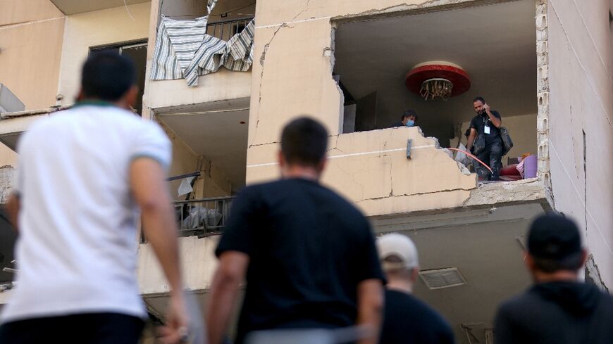 Lebanese inspect the damage to a building struck in Beirut's southern suburbs