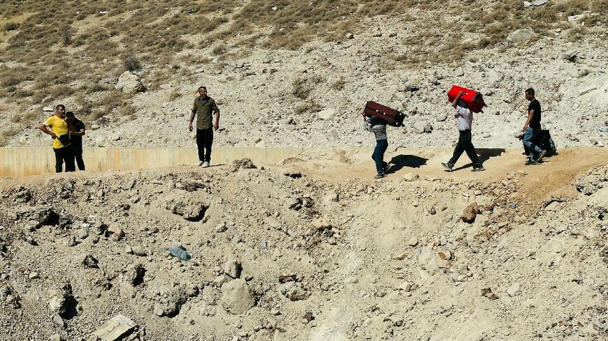 People walk across a crater caused by an Israeli strike along the Lebanon-Syria border