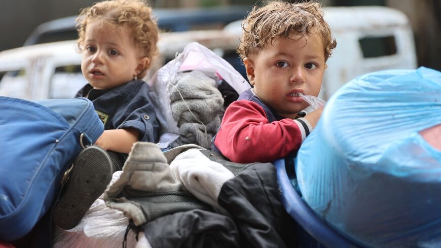 Palestinian children sit with family belongings in the back of a makeshift trolley as they arrive in Gaza City after evacuating their homes in Jabaliya