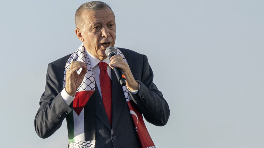 Turkish President Recep Tayyip Erdogan wears a scarf with both Turkish and Palestinian flags as he addresses a rally organized by the AKP party in solidarity with the Palestinians in Gaza, in Istanbul on Oct. 28, 2023. 