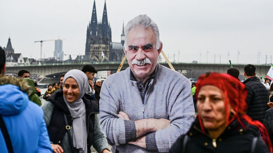 Supporters of the Kurdish community demonstrate with flags and banners on the occasion of the 25th anniversary of the arrest of Kurdistan Workers Party (PKK) leader Abdullah Ocalan (portrait on the placard at C) on the banks of the Rhine river in Cologne, western Germany, on February 17, 2024. Abdullah Ocalan, who founded the Kurdistan Workers' Party (PKK) nearly half a century ago and has languished in solitary confinement on a prison island since 1999, is hailed as an icon by some Kurds but denounced by m