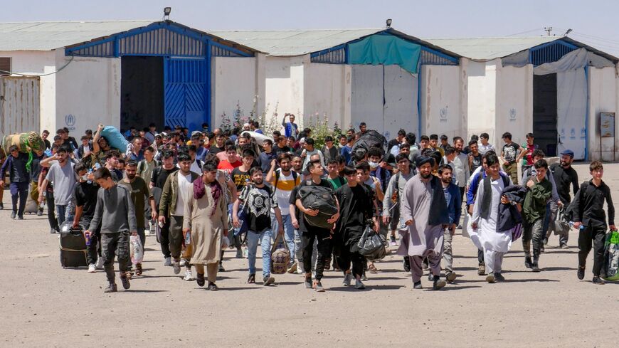 Afghan refugees walk with their belongings after deporting back from Iran at the Islam Qala border between Afghanistan and Iran, in the western Herat province on May 30, 2024. 