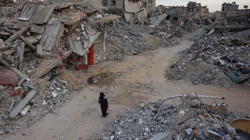 A woman walks past destroyed buildings in Khan Younis in the southern Gaza Strip amid the ongoing war between Israel and the Palestinian militant group Hamas in the besieged Palestinian territory, October 17, 2024.