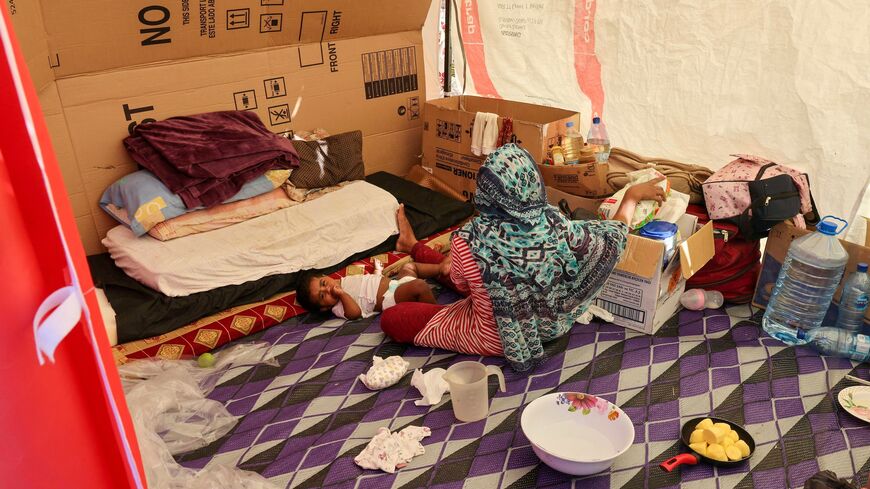 A displaced Bangladeshi woman and her child sit inside their makeshift shelter on the seaside promenade in the Biel area of Beirut, Oct. 17, 2024.