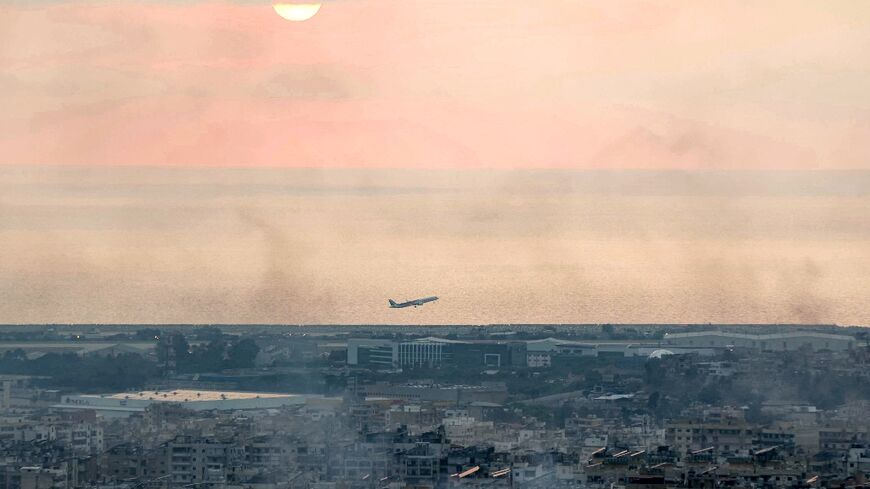 A Middle East Airlines plane takes off from Beirut airport amidst smoke rising from nearby sites targeted overnight by Israeli air strikes