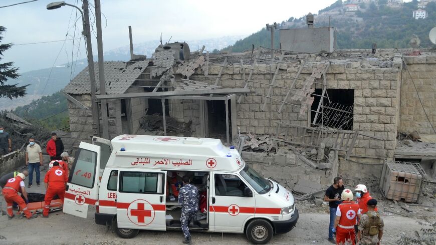 Paramedics with the Lebanese Red Cross transport a body unearthed from the rubble into an ambulance at the site of an Israeli airstrike that targeted the northern Lebanese village of Aito on October 14, 2024