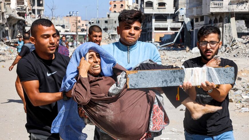 Several people took turns carrying a woman out of Jabalia refugee camp, her injured leg in a makeshift splint made of salvaged furniture