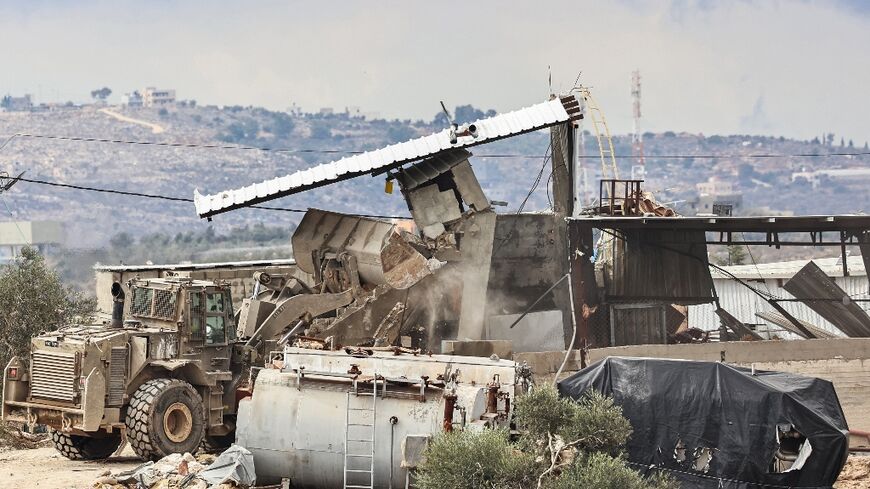 An Israeli military bulldozer demolishes buildings in Qabatiyah