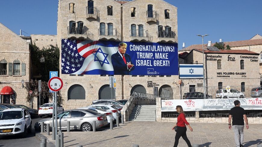 People in Jerusalem walk past a billboard congratulating US President-elect Donald Trump on November 8, 2024