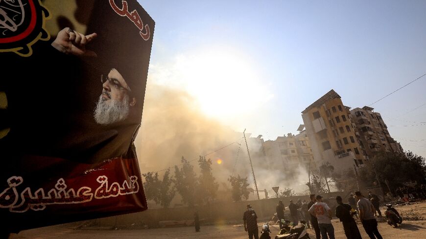 Smoke rises from the ruins of a south Beirut building hit by a pre-dawn Israeli air strike just metres (yards) from a huge poster of slain Hezbollah leader Hassan Nasrallah