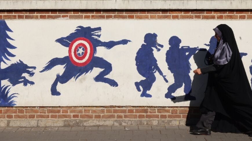 An Iranian woman walks past a mural on the side wall of the former US embassy in Tehran, the day after the presidential election won by Donald Trump