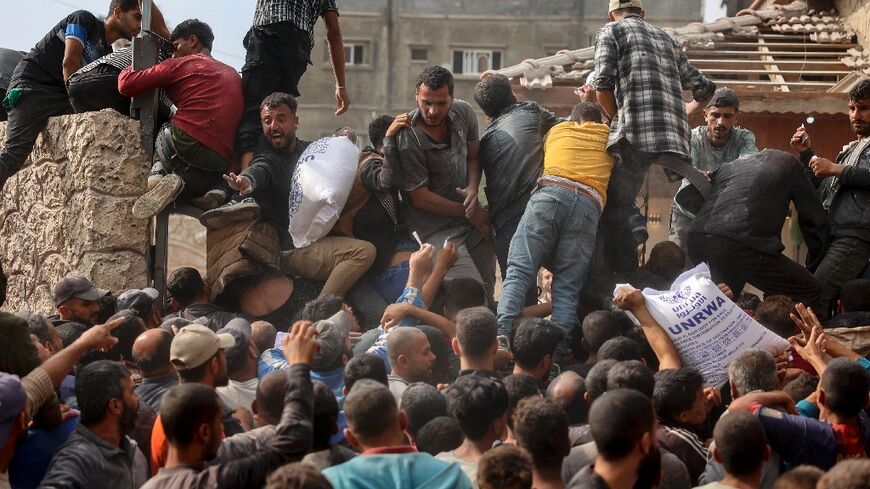 People scramble to receive sacks of flour at a United Nations Relief and Works Agency (UNRWA) aid distribution centre in Deir el-Balah, central Gaza