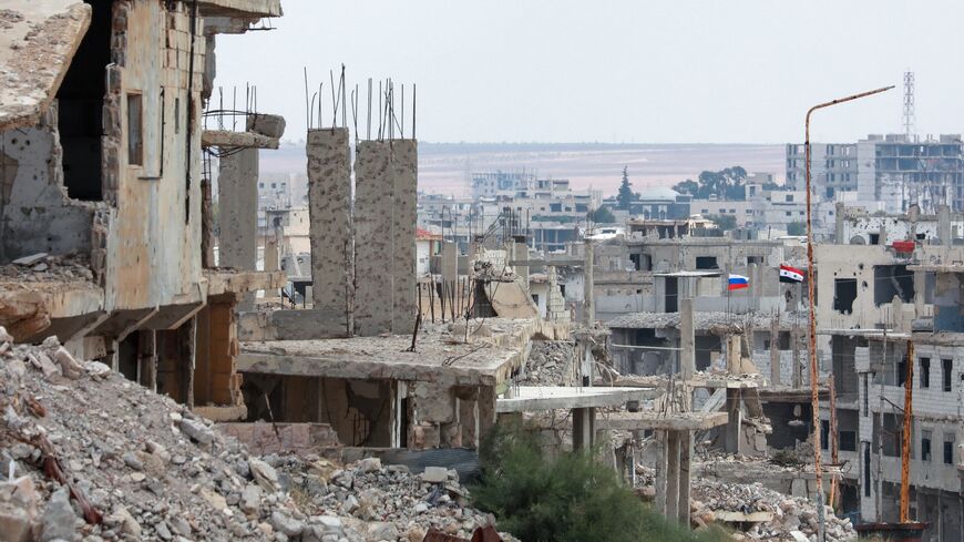 A picture taken during a tour organized by the Syrian Ministry of Information shows flags of Russia and Syria atop a damaged building in the district of Daraa al-Balad of Syria's southern city of Daraa, on Sept. 12, 2021.