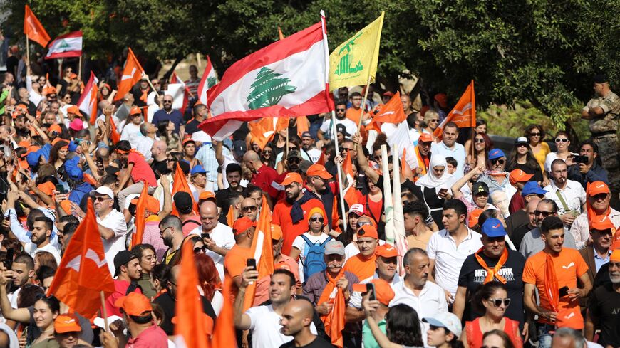 Supporters wave national flags as well as orange flags of the Free Patriotic Movement and the yellow flag of the Hezbollah movement, as Lebanon's outgoing President Michel Aoun leaves the presidential palace in Babda, at the end of his mandate, east of the capital Beirut, on October 30, 2022.