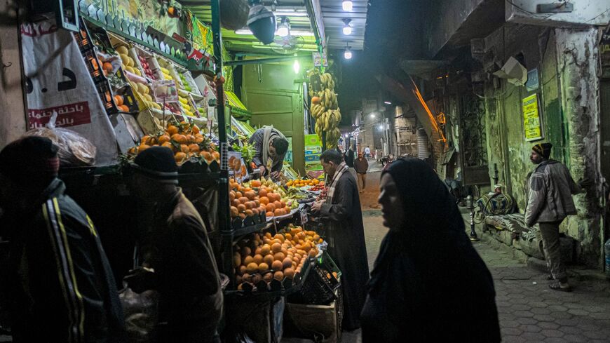 People walk past a fruit seller's stall in the Azhar district of Egypt's capital, Cairo, on Jan. 16, 2023.