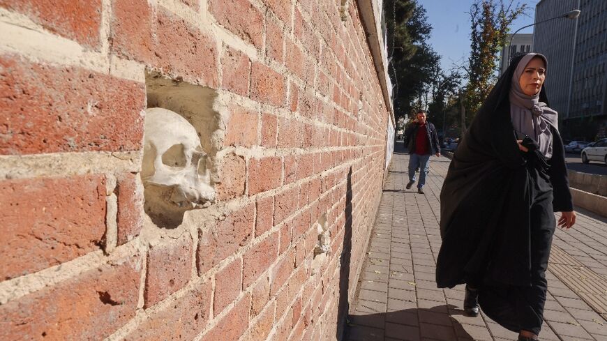 A woman walks past the former US embassy compound in Tehran, which has skulls embedded in the wall