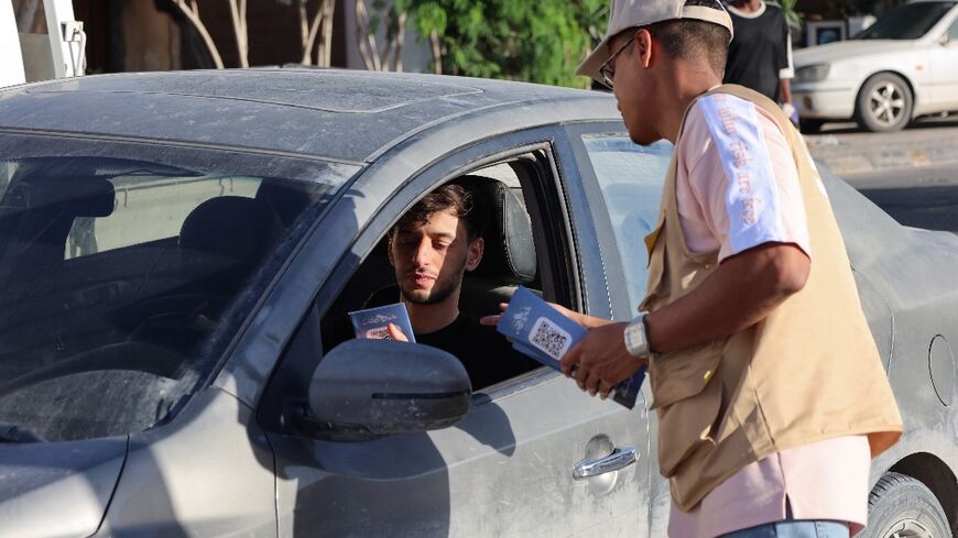 A campaigner hands an election leaflet to a driver ahead of the vote in Misrata