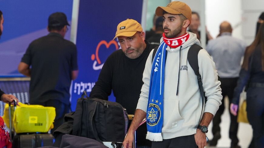 A fan wearing Maccabi Tel Aviv and Ajax scarves arriving at the Ben Gurion International Airport near Israel's Tel Aviv