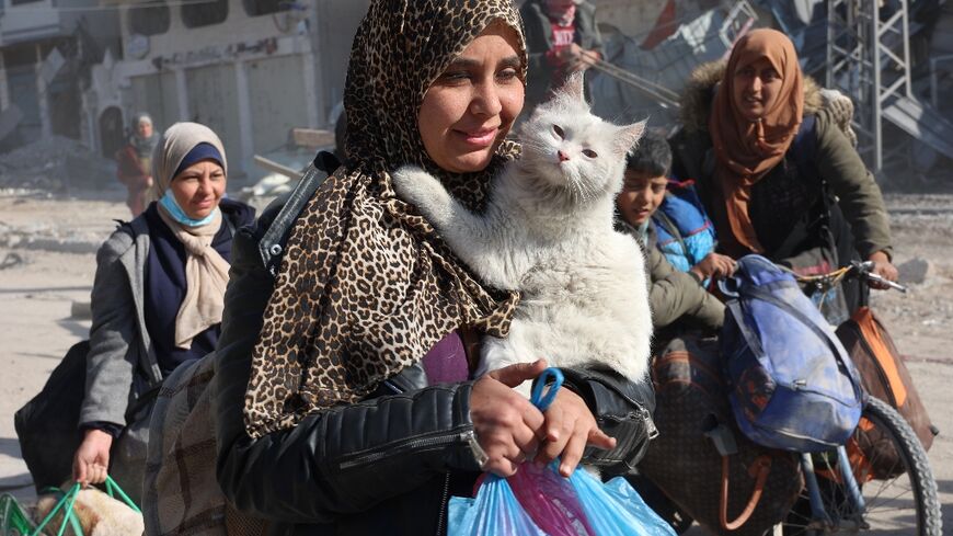 A Palestinian woman carries her cat as displaced people from Beit Lahia arrive in Jabalia in the northern Gaza Strip on December 4, 2024