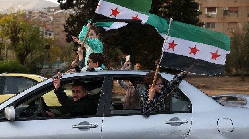 People celebrate with the Syrian opposition flag in Damascus