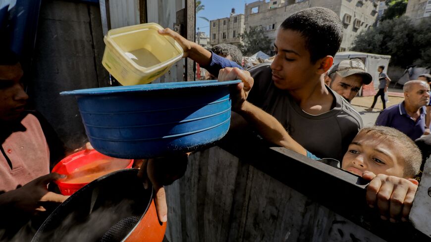 Children reach out with bowls, hoping to receive food during a distribution in Gaza City, with the population facing increasing hunger due to closed crossings. Oct. 21, 2024.