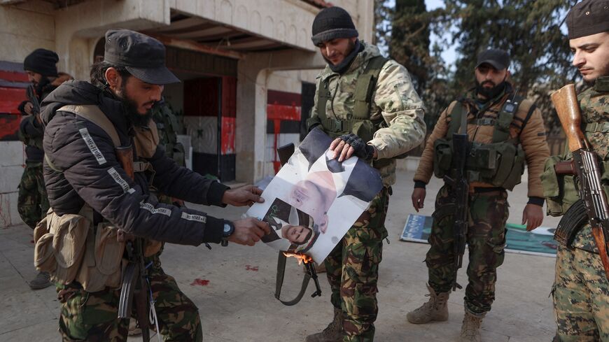 Fighters set alight a picture of Syrian President Bashar al-Assad in front of a building that was seized by jihadists in the area of Zarbah on Nov. 29, 2024. 